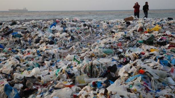 In this Monday, Jan. 22, 2018, photo, a man takes photos of piles of garbage washed on shore after an extended storm battered the Mediterranean country at the Zouq Mosbeh costal town, north of Beirut, Lebanon. Environmentalists say a winter storm has pushed a wave of trash onto the Lebanese shore outside Beirut, stirring outrage over a waste management crisis that has choked the country since 2015. (AP Photo/Hussein Malla)