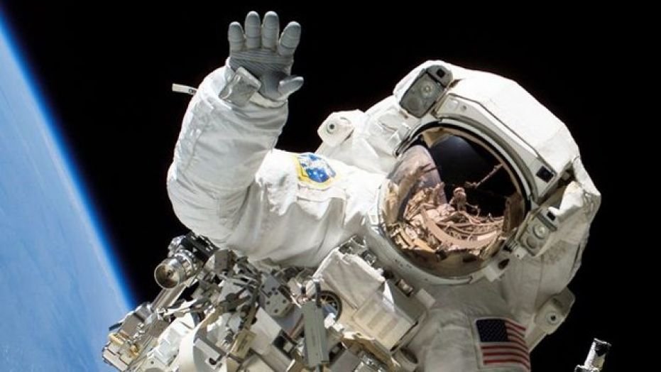 Astronaut Heidemarie M. Stefanyshyn-Piper waves at the camera during a spacewalk.