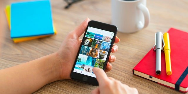 Woman using smartphone on a wooden desk. 